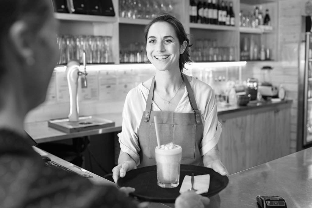 Coffee shop barista smiling next to an espresso machine