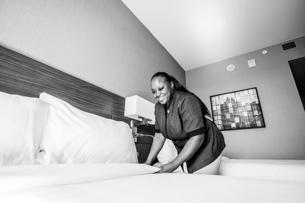Hotel worker changing bed linen in hotel room.