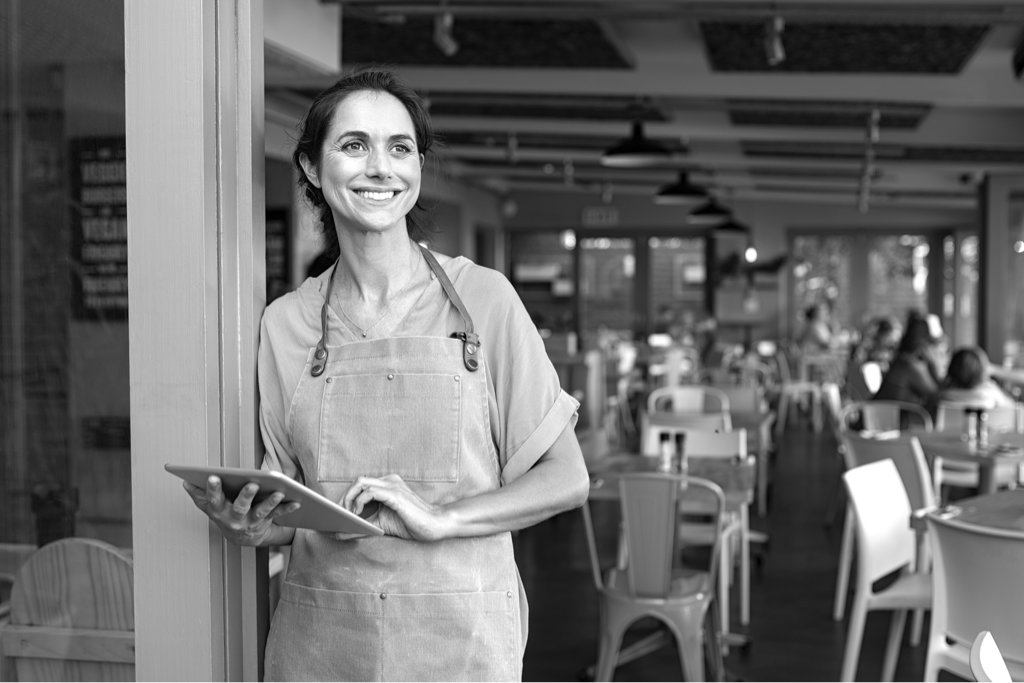 Independent business women wearing an apron and holding an tablet in her cafe